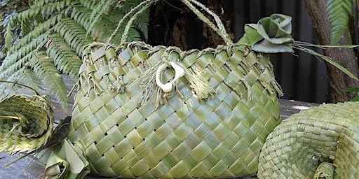 Handwoven green flax bag with decorative designs, displayed outdoors with surrounding natural greenery.